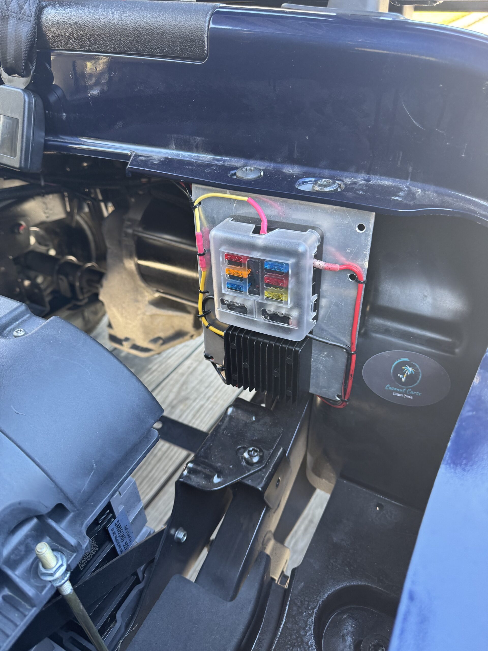 Close view of golf cart electrical work with a Coconut Carts service label